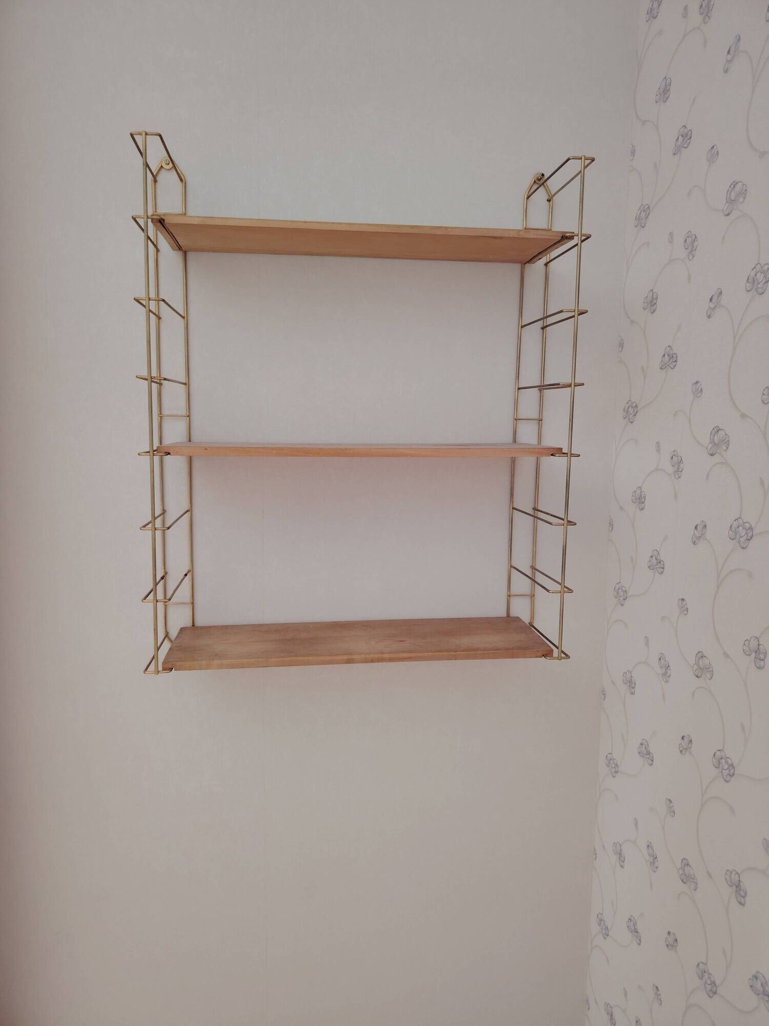 Vintage modular wall shelf in golden steel wire and wood from the 1950s.
