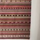 Large Indian rug with red, yellow, and white stripes and geometric fringes.