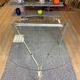Round dining table with a glass top and brushed metal triangular frame.