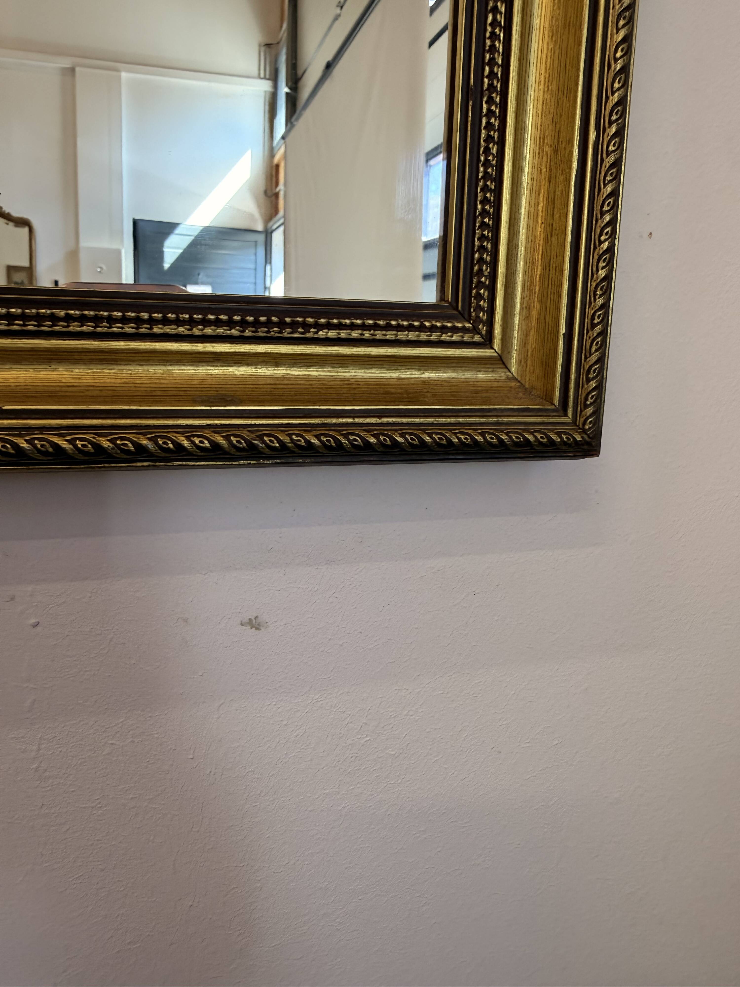Vintage rectangular wall mirror with a golden wooden frame.