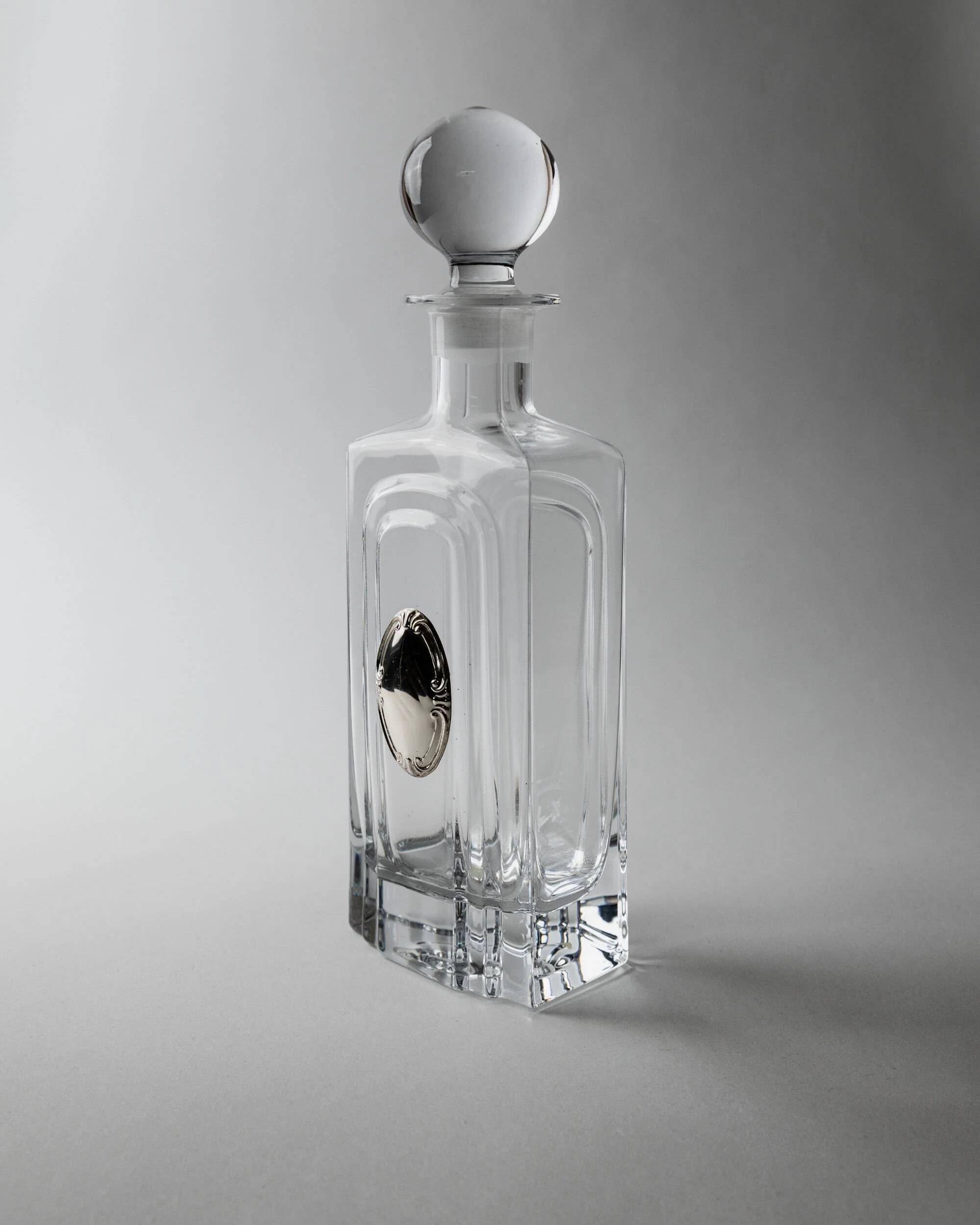 Vintage glass decanter from the 1980s, transparent glass with a silver plate and spherical stopper.