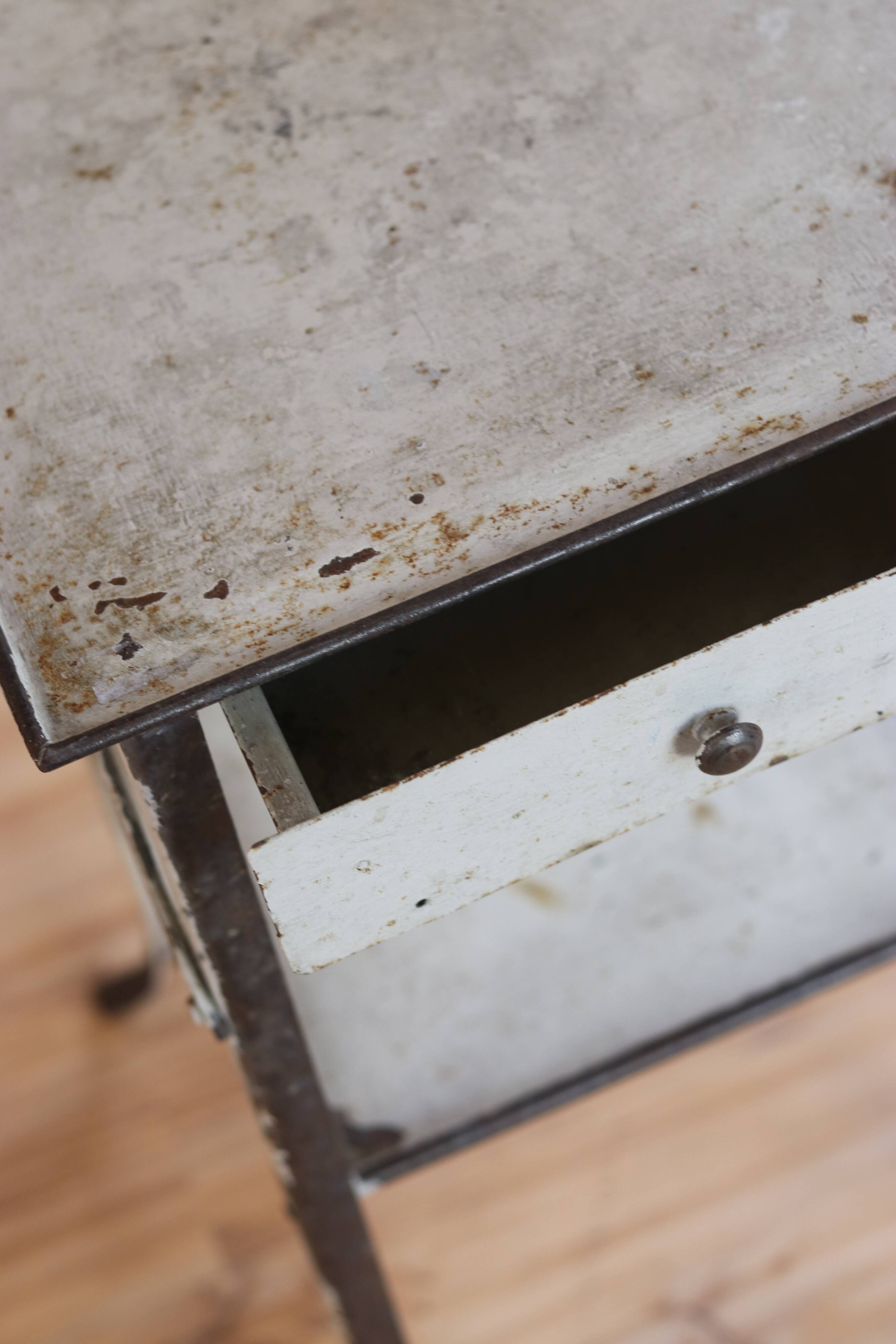 Painted metal side table, patinated white, with a drawer and two shelves