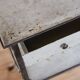 Painted metal side table, patinated white, with a drawer and two shelves