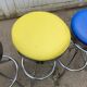 Set of 5 vintage swivel bar stools in blue, red, orange, and yellow.