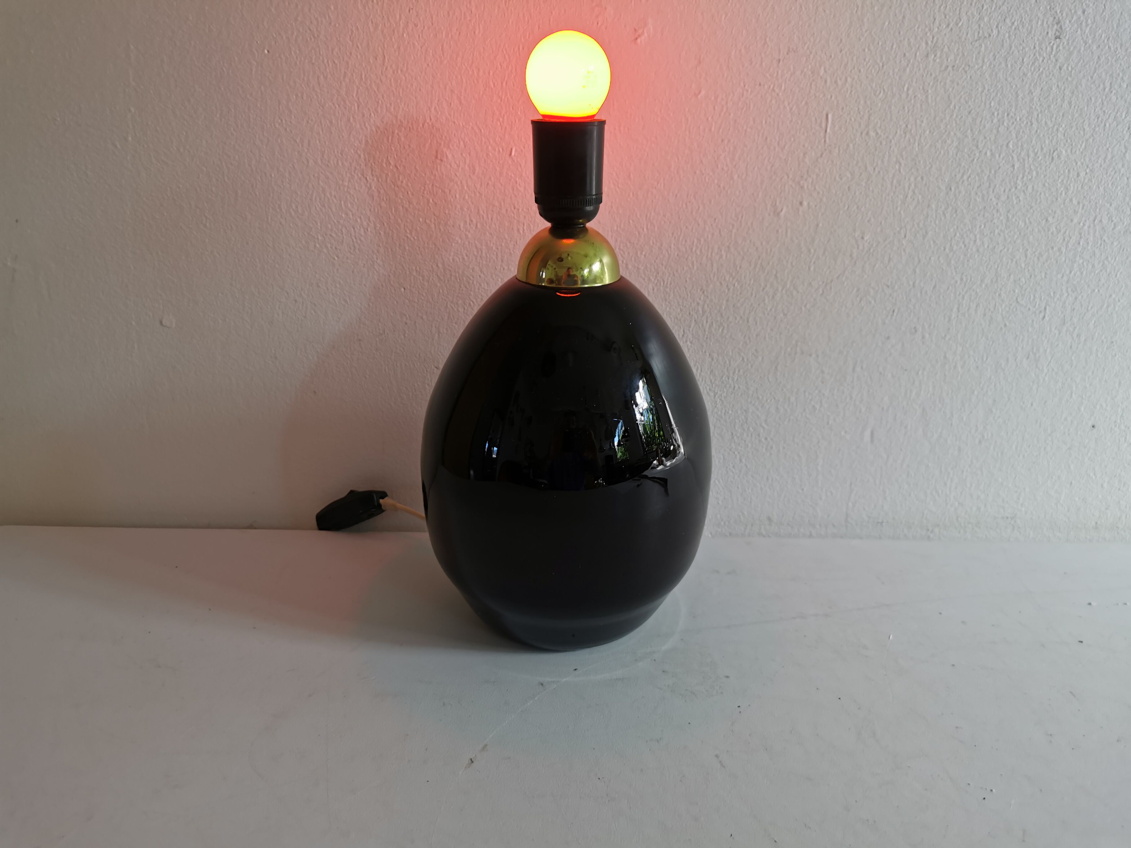 Table lamp, made of handmade coal-black glass, with brass coloured top.