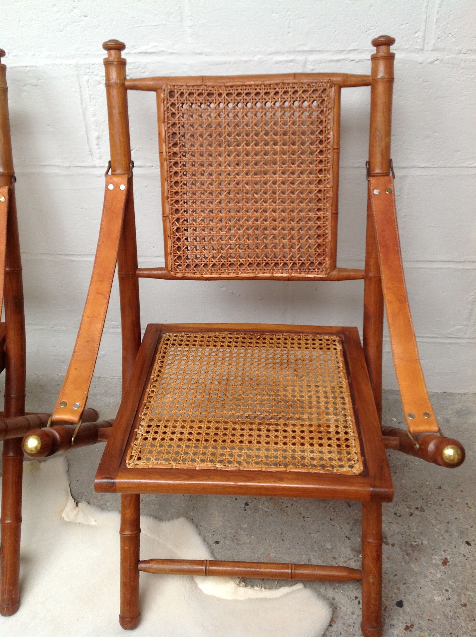 Pair of folding chairs in bamboo and caning, leather and brass