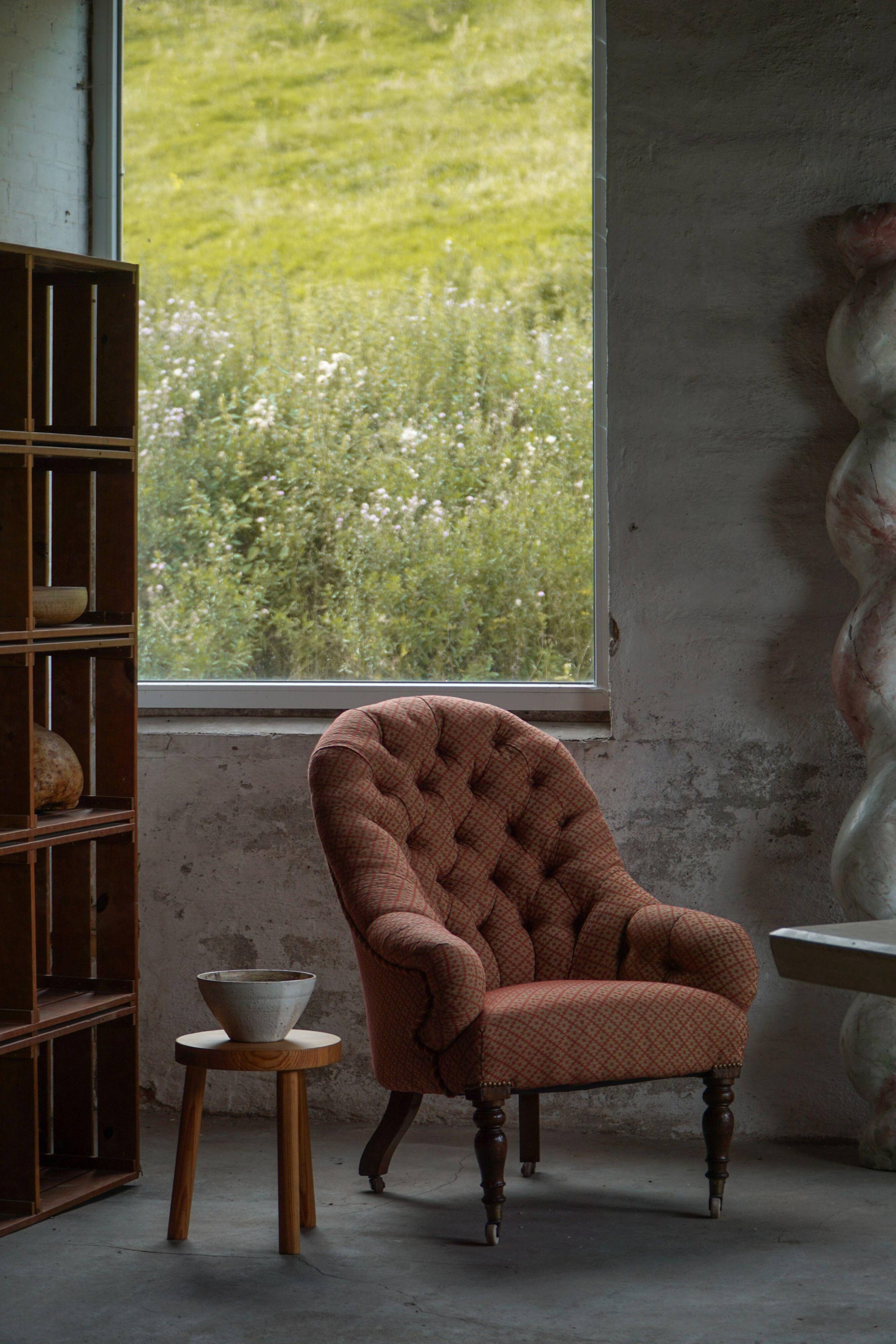 Victorian mahogany armchair, with wheels and coloured fabric, England, early 1900s.