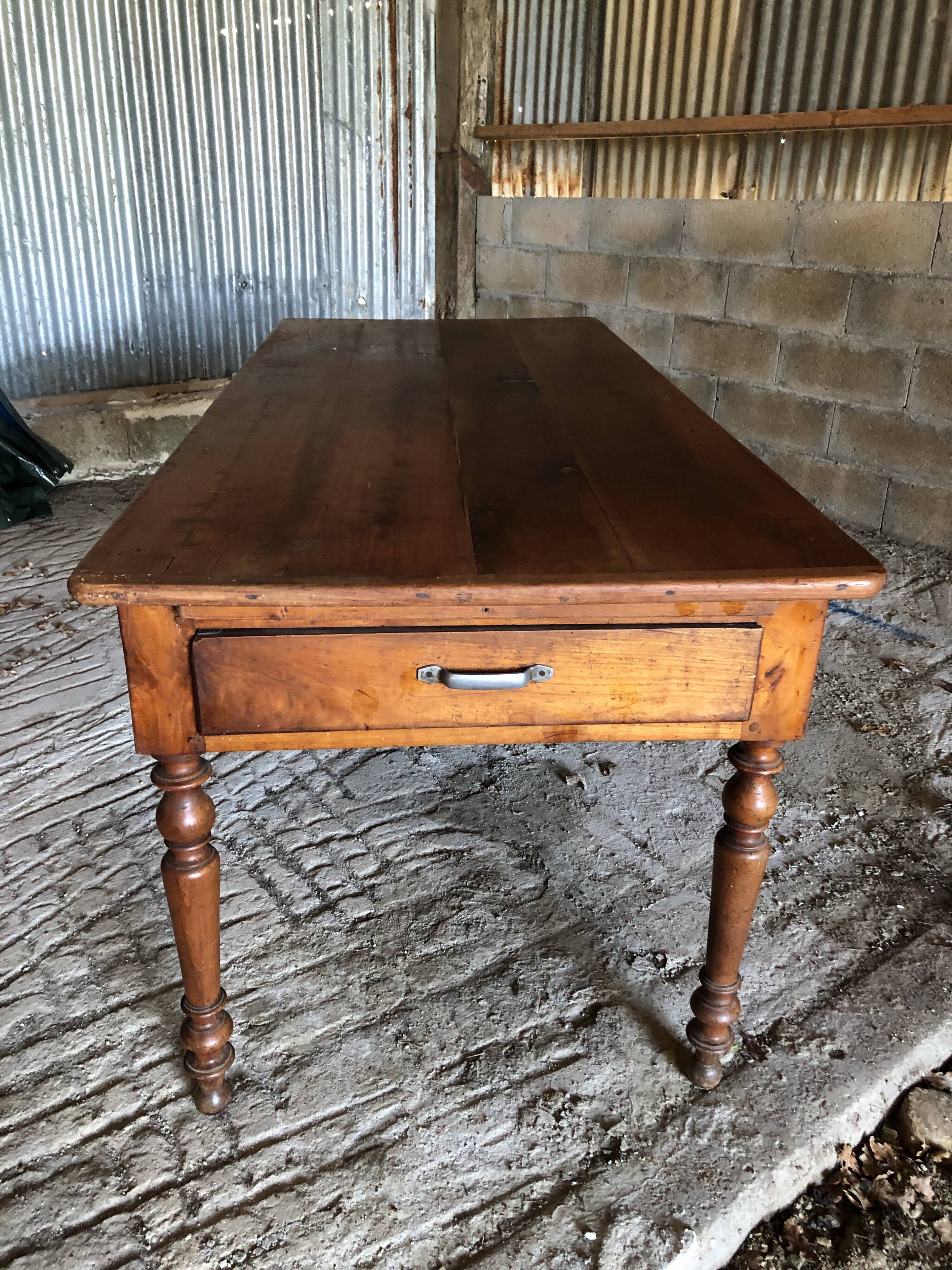 Antique Louis Philippe style farm table in solid cherry wood with turned base.