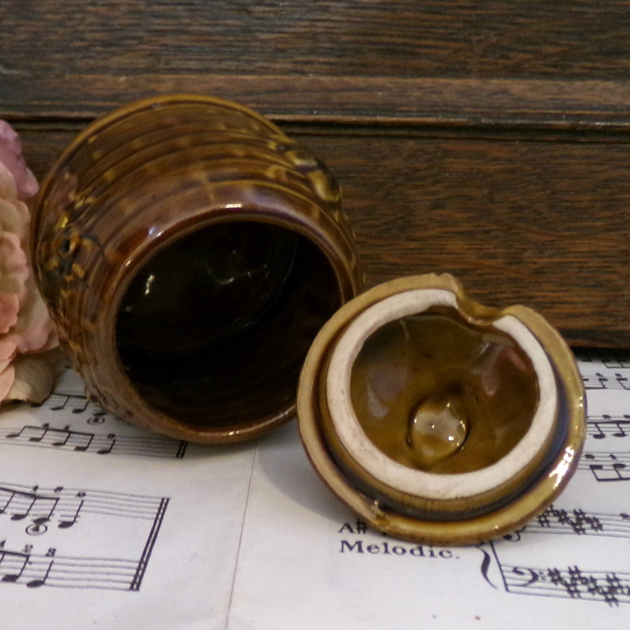 Honey pot in the shape of a hive decorated with bees.