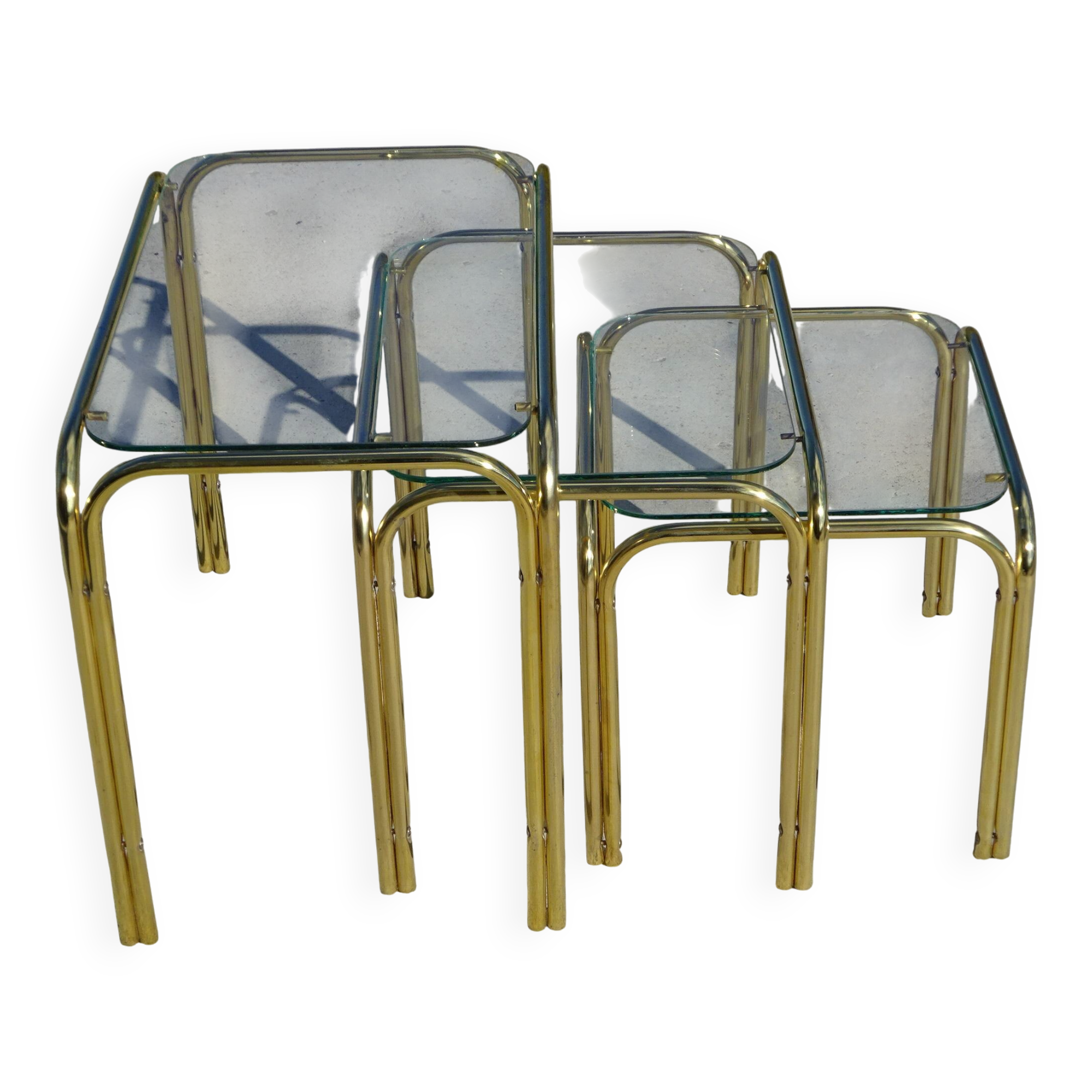 Nested tubular tables in gold metal.