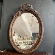 Antique oval mirror in carved wood and Louis XVI style knot