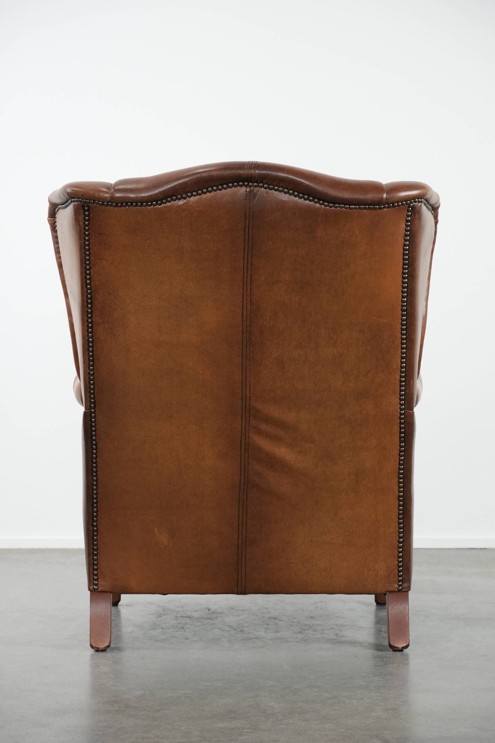 Fauteuil à oreilles de style anglais couleur cognac en cuir de vache.