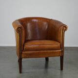 Neat and subtle sheepskin club chair, finished with decorative studs and a fixed seat cushion