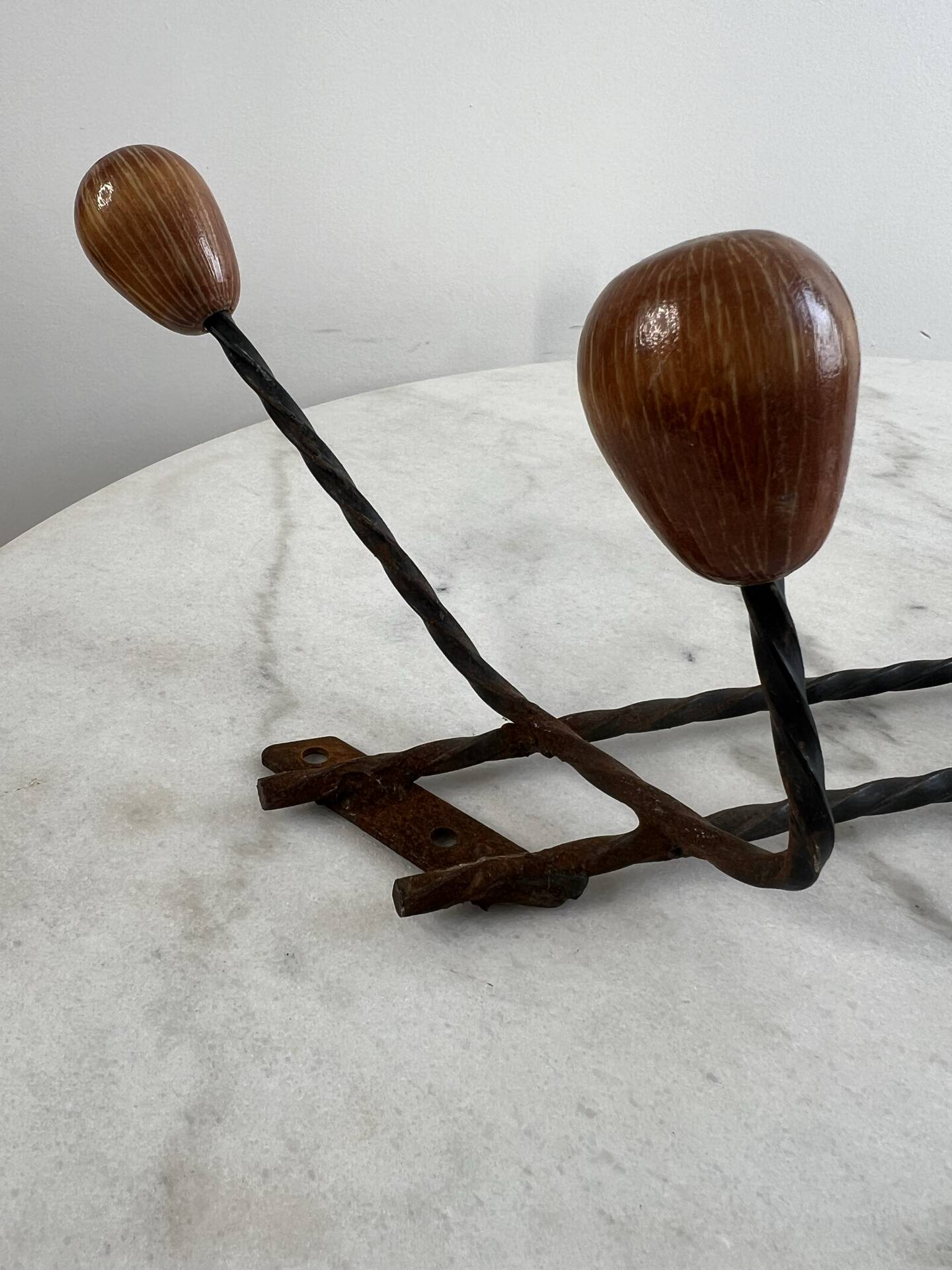 Wall-mounted coat rack in wrought iron with turned wooden knobs.