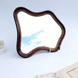 Antique wall mirror in carved wood with a wavy shape and a golden trim.