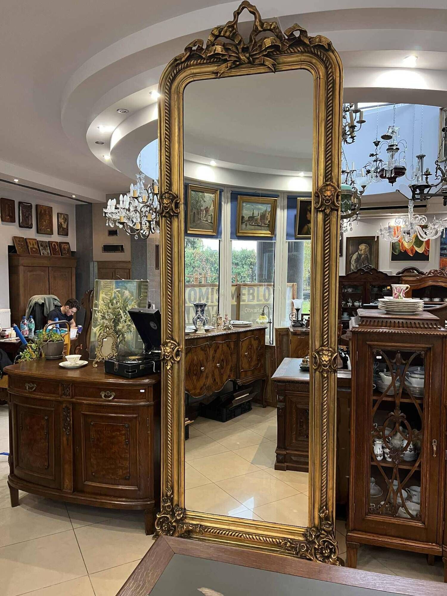 French palace mirror with bow and lion heads, gilded frame.