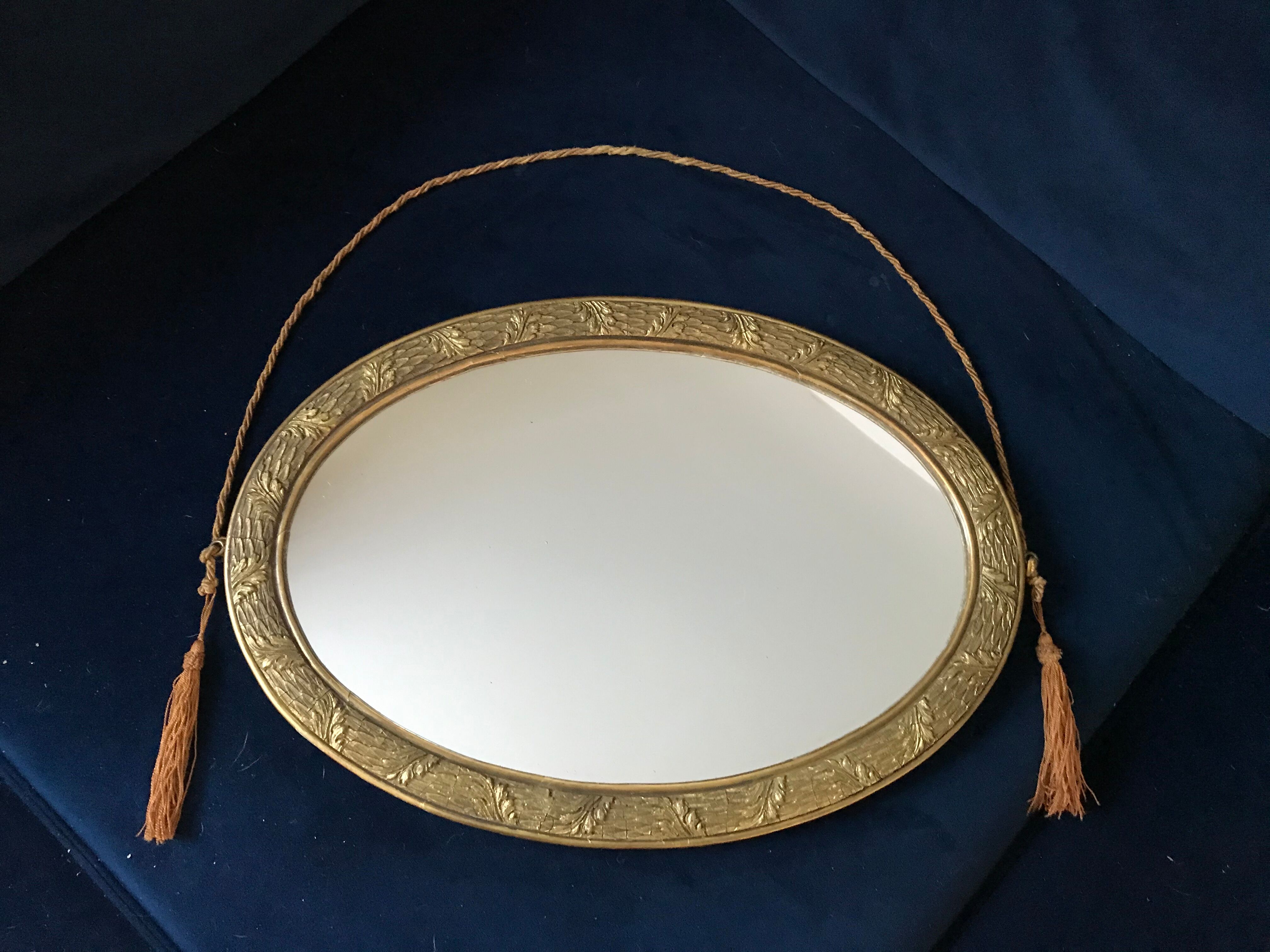 Golden oval mirror with its wooden frame and stucco on wood, nicely cracked by time