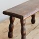 Vintage rectangular stool in dark wood with turned legs.