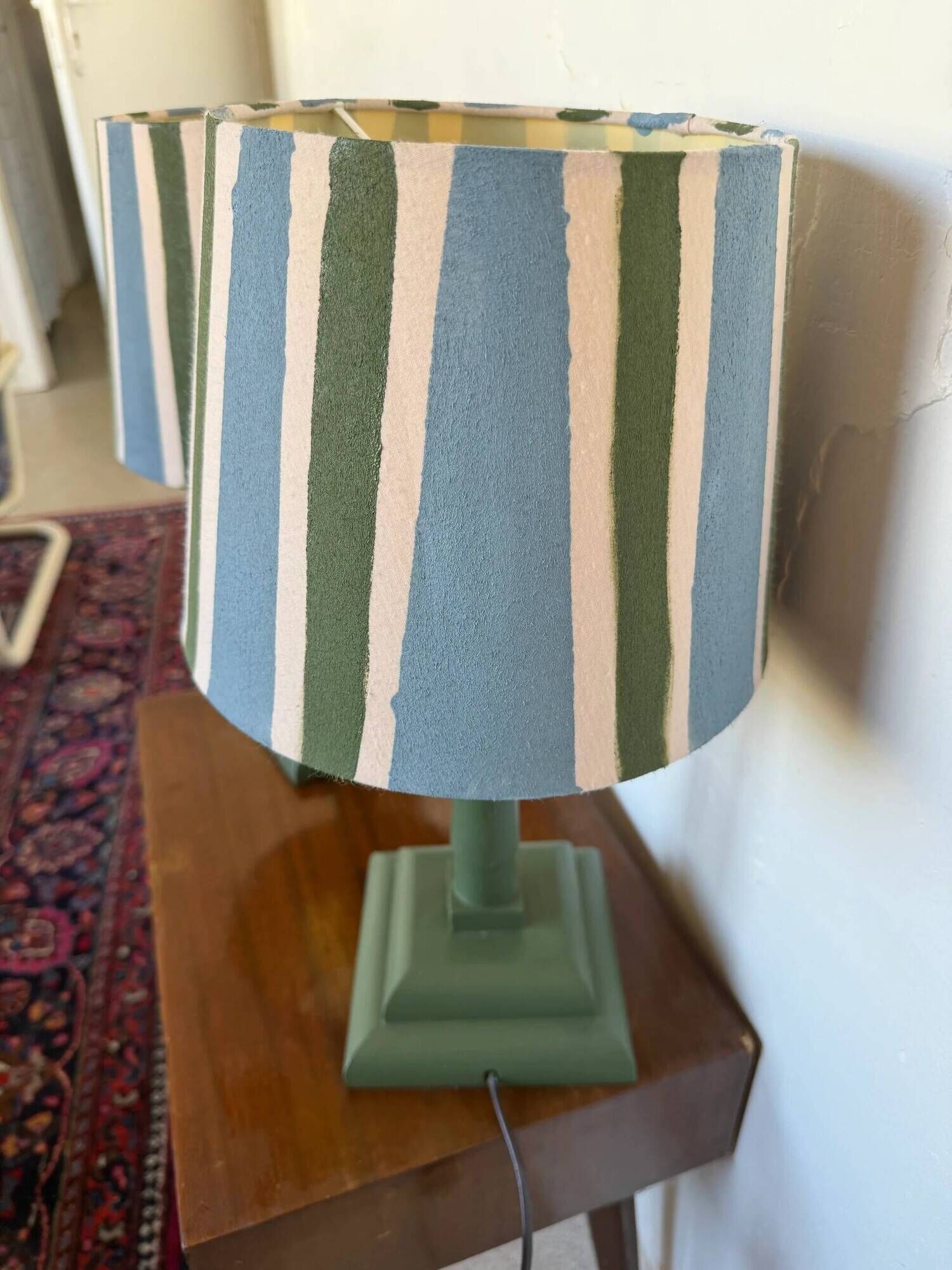 Pair of vintage wooden lamps with their striped beige, blue, and green shades.