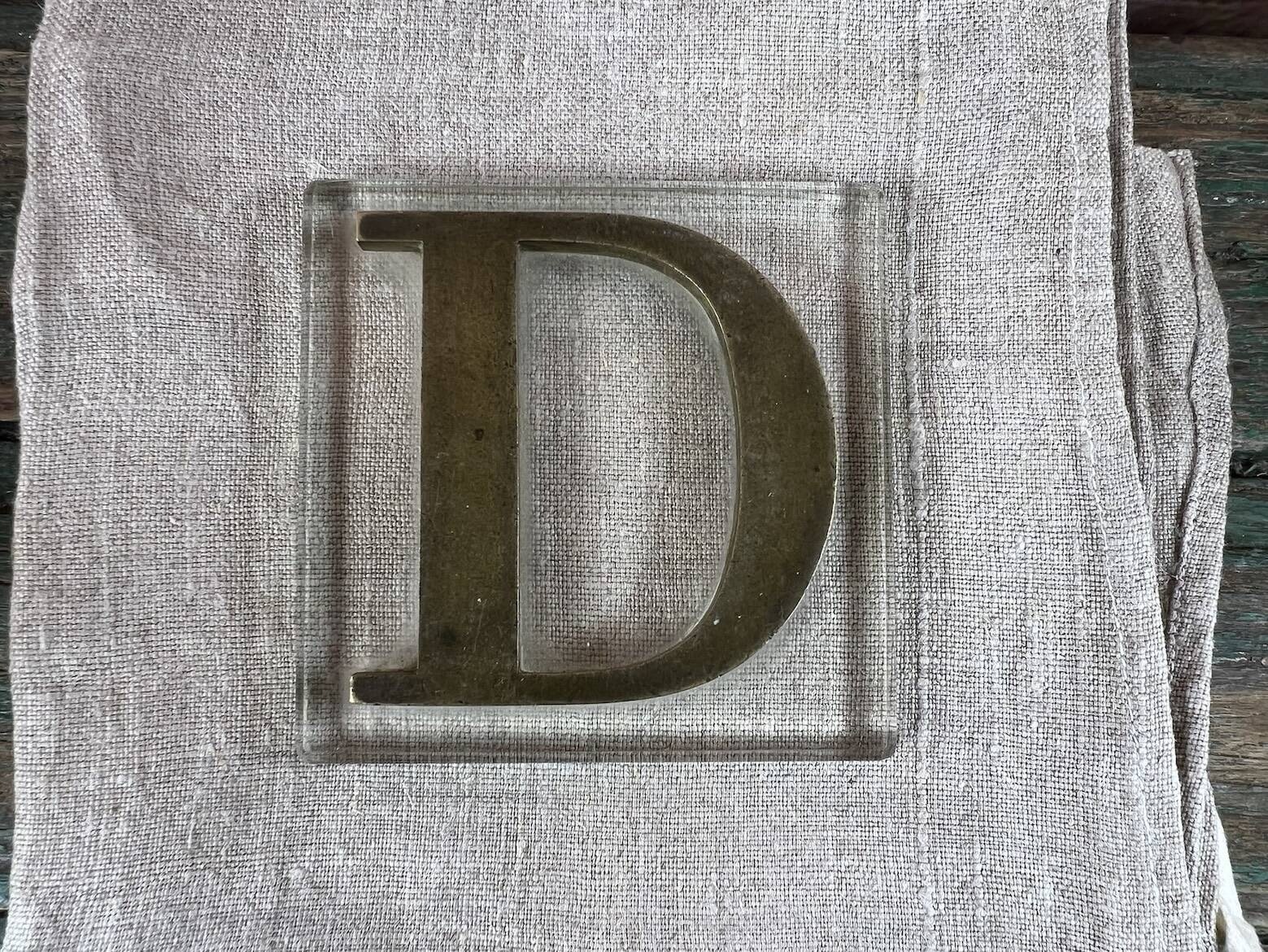 Metal letter D on glass plate