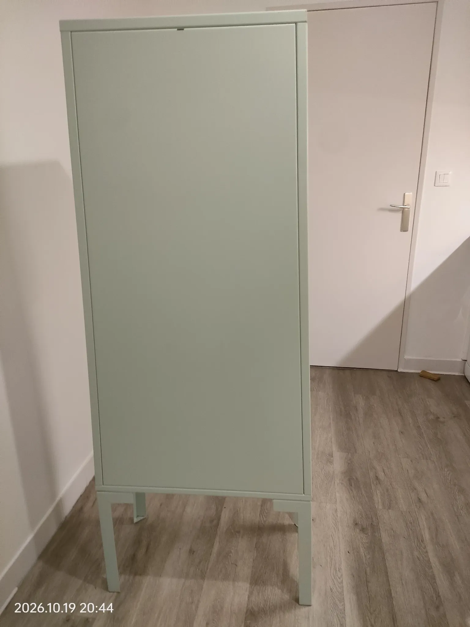 Vintage sage green metal wardrobe with louvered doors and coral handles.