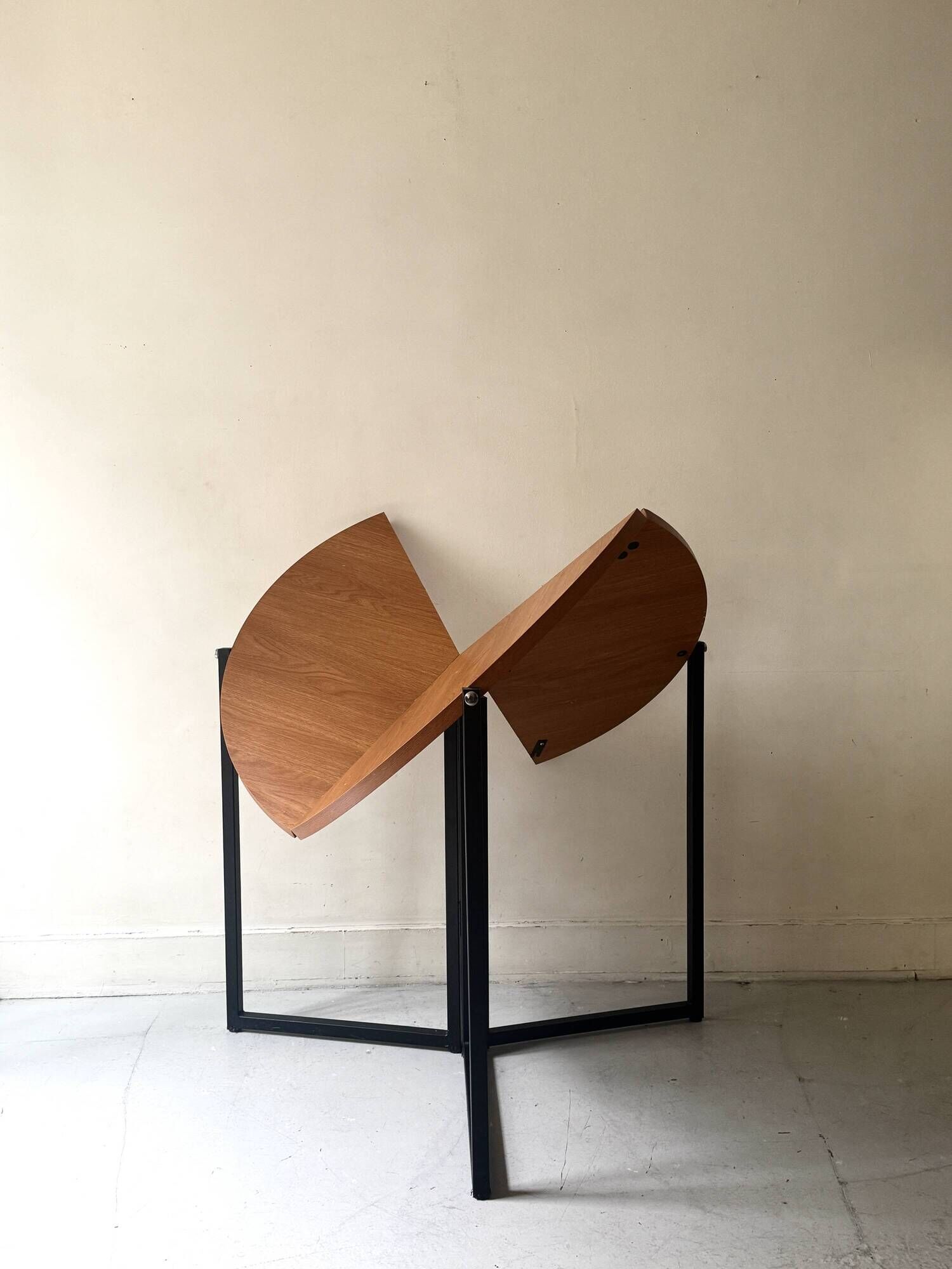 Modernist round folding dining table in wood and metal.