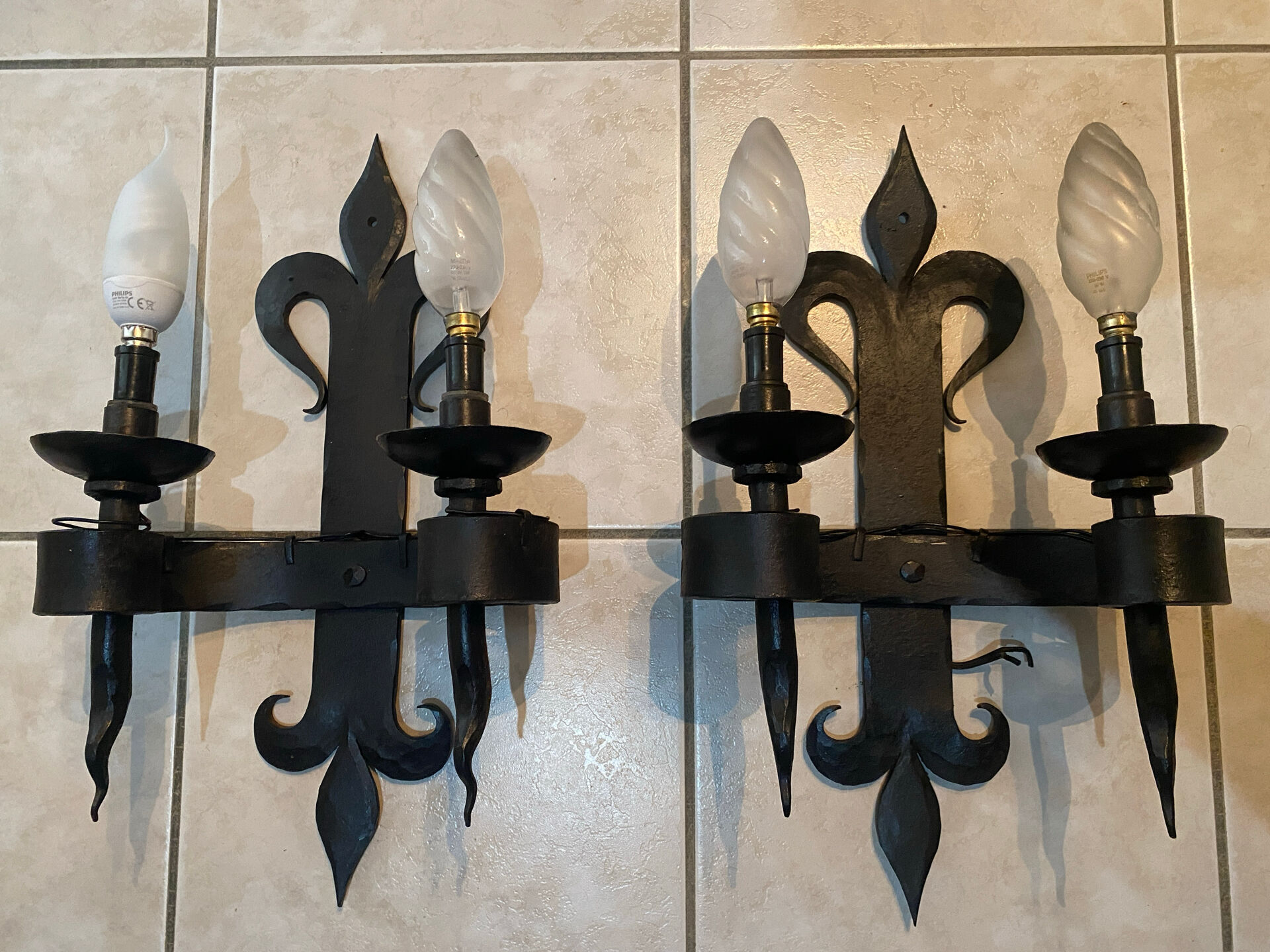 Pair of wrought iron wall lights in fleur-de-lis château style.