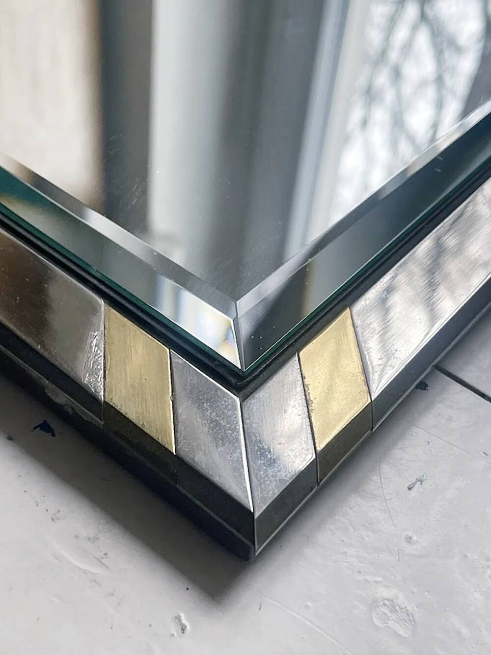 Faceted modernist wall mirror in steel and brass, geometric mixed metal frame 1970s.