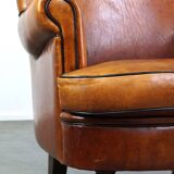 Subtle sheepskin wing chair in good condition on brass front wheels