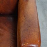 Sheepskin leather armchair in a cognac color with black piping