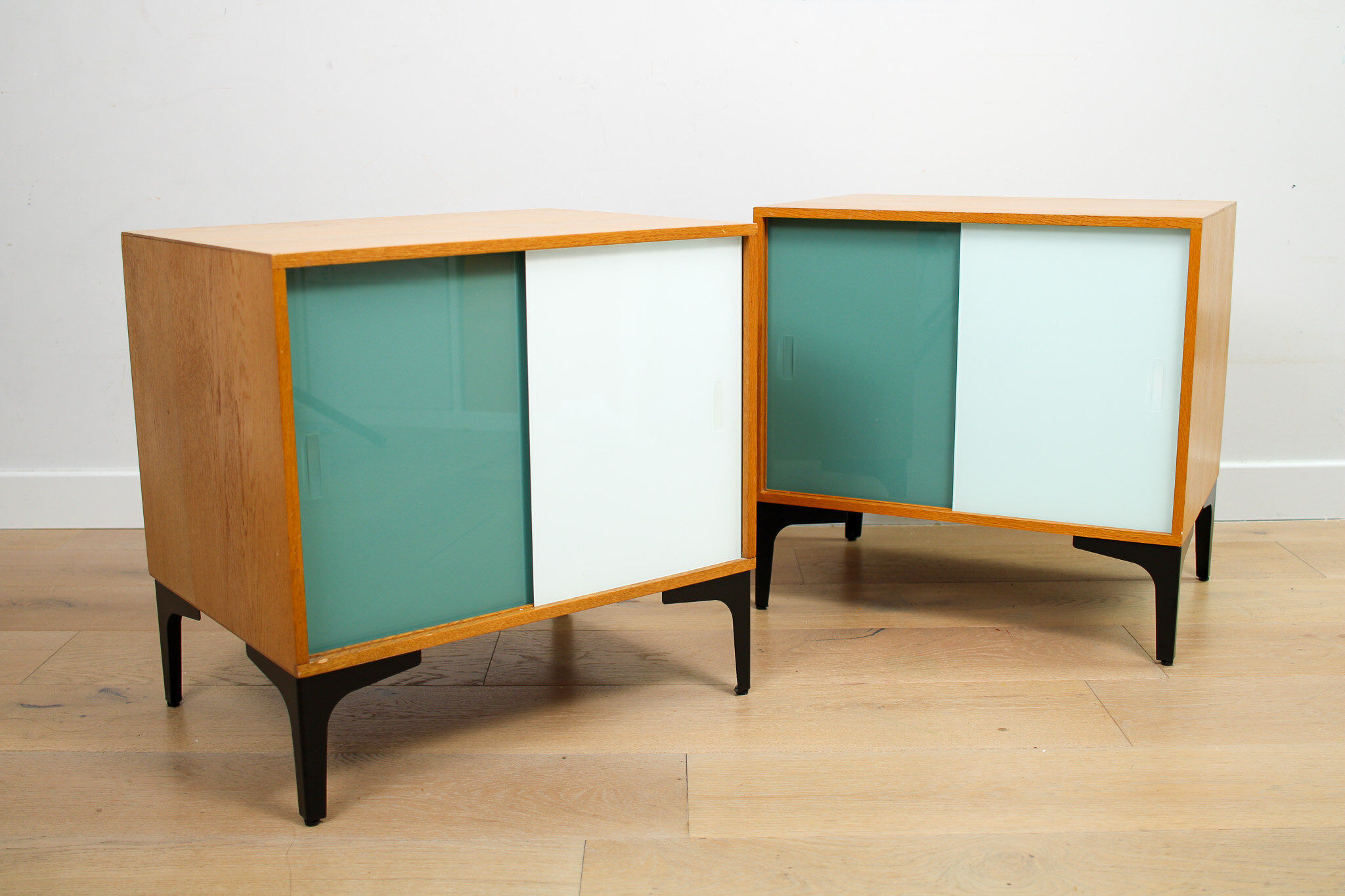 A pair of vintage mid-century bedside tables with glass sliding doors