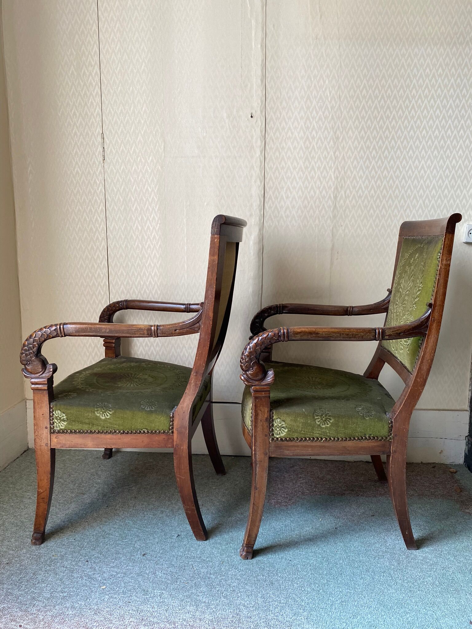 Paire de fauteuils empire en noyer teinté, tissus vert motif de palmette, sculptés têtes de dauphin