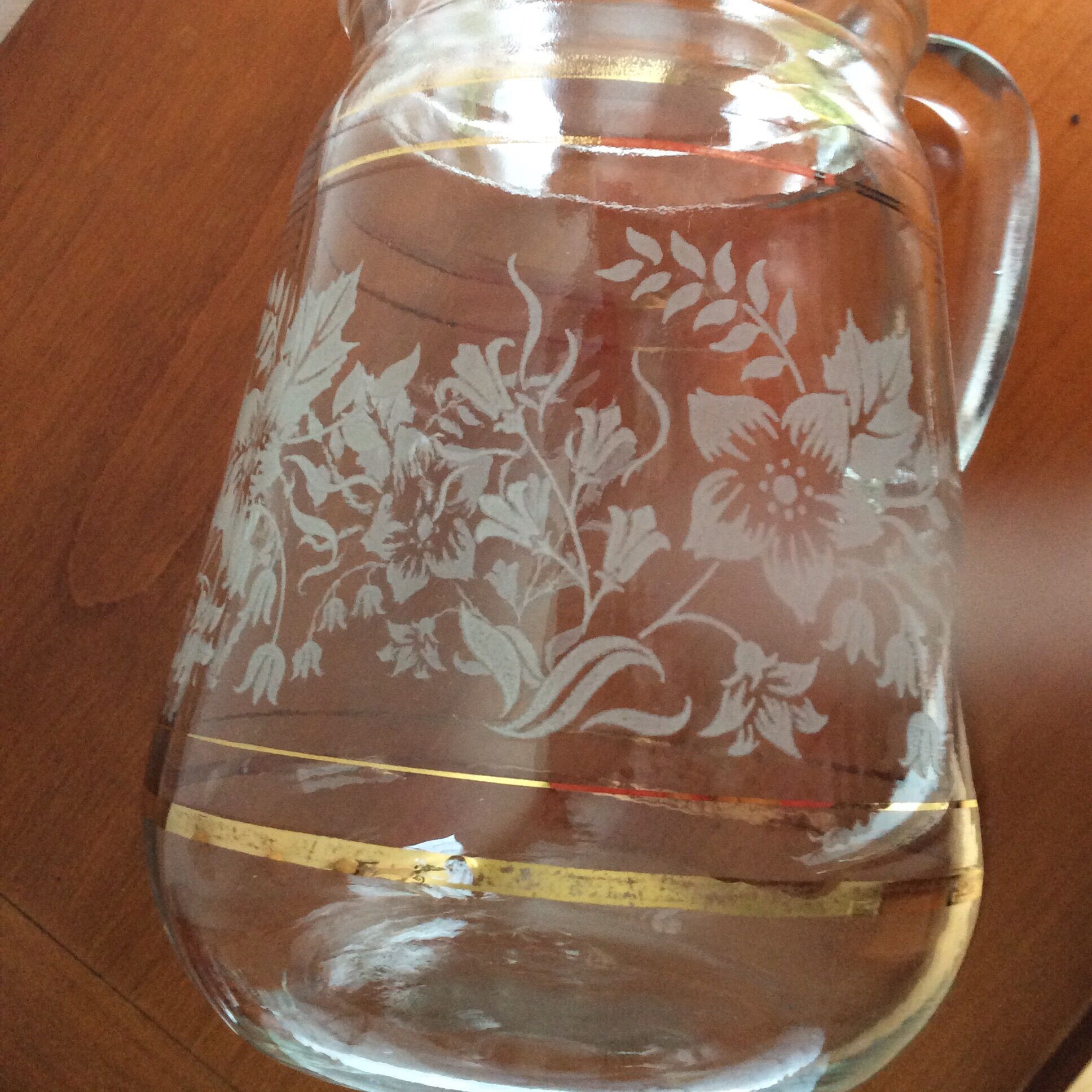 Old glass water pitcher with white flowers in relief with gold edging
