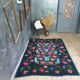 Handwoven floral wool rug, black background with pink roses and geometric design 207x144cm