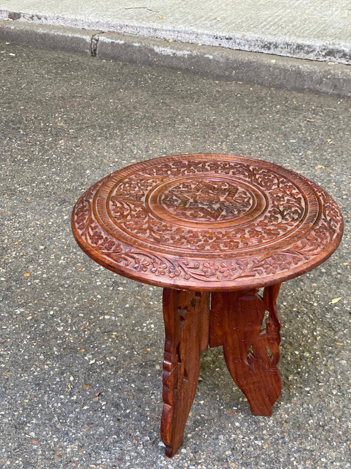 Round folding side table made of carved solid wood.