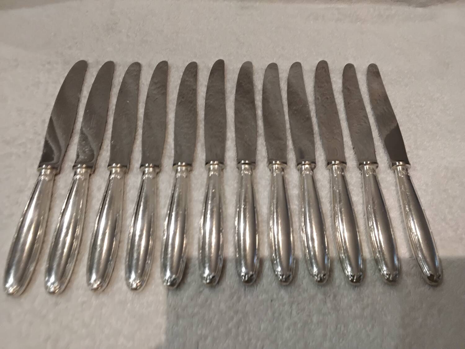 12 silver-plated table knives, Christofle goldsmith ribbons