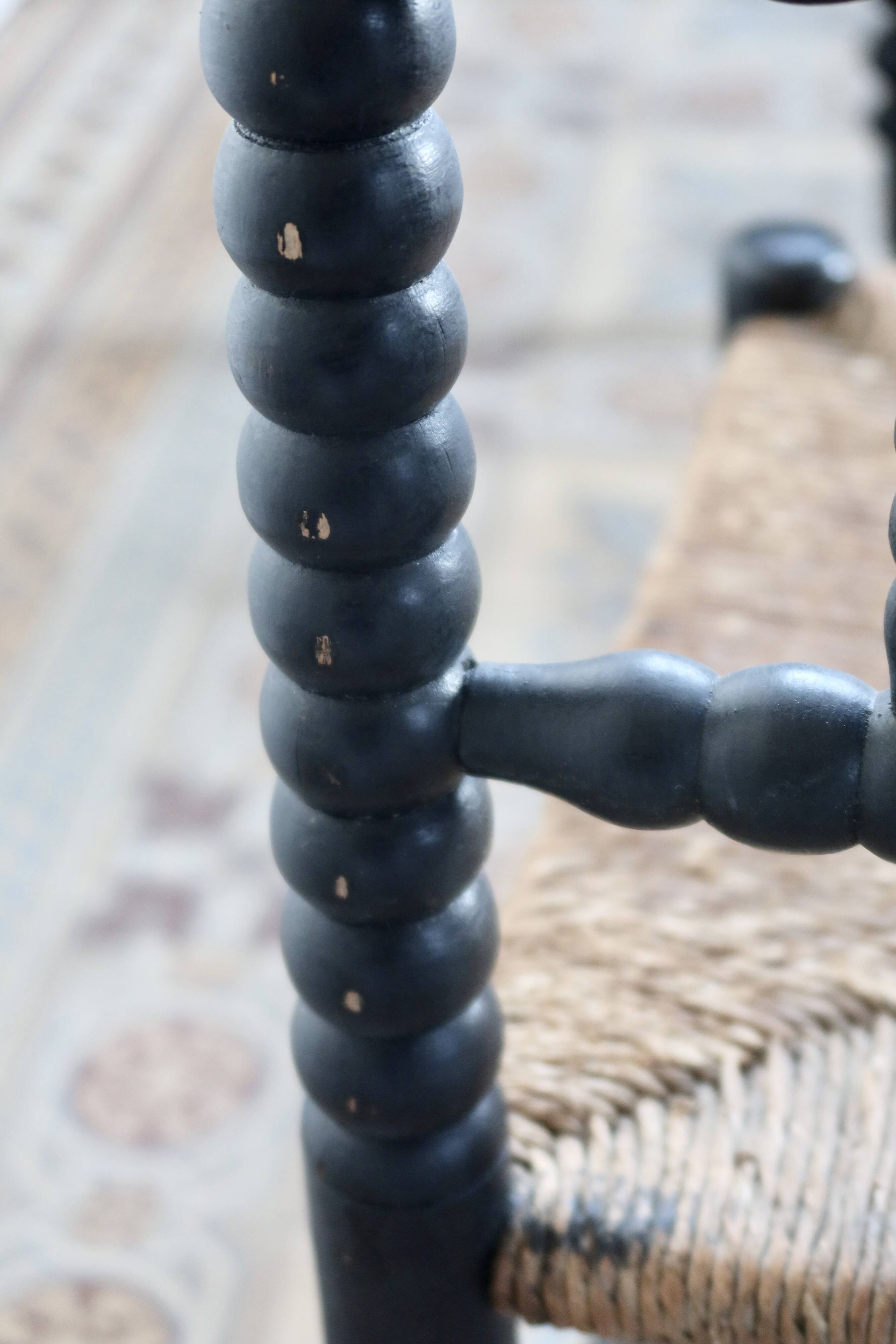 Antique black turned wood corner chair with a straw seat.