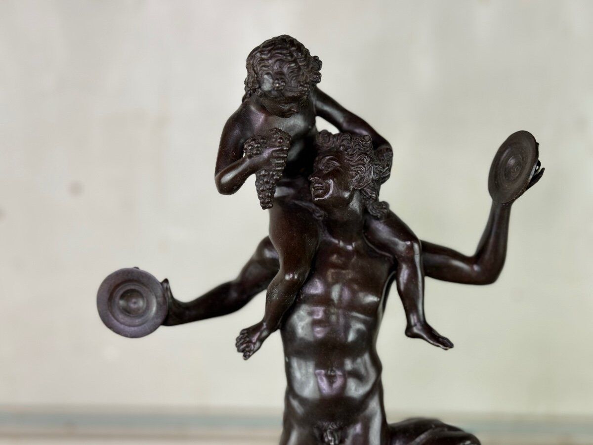 Dionysus on the shoulders of a satyr, bronze after the antique on a yellow Siena base.