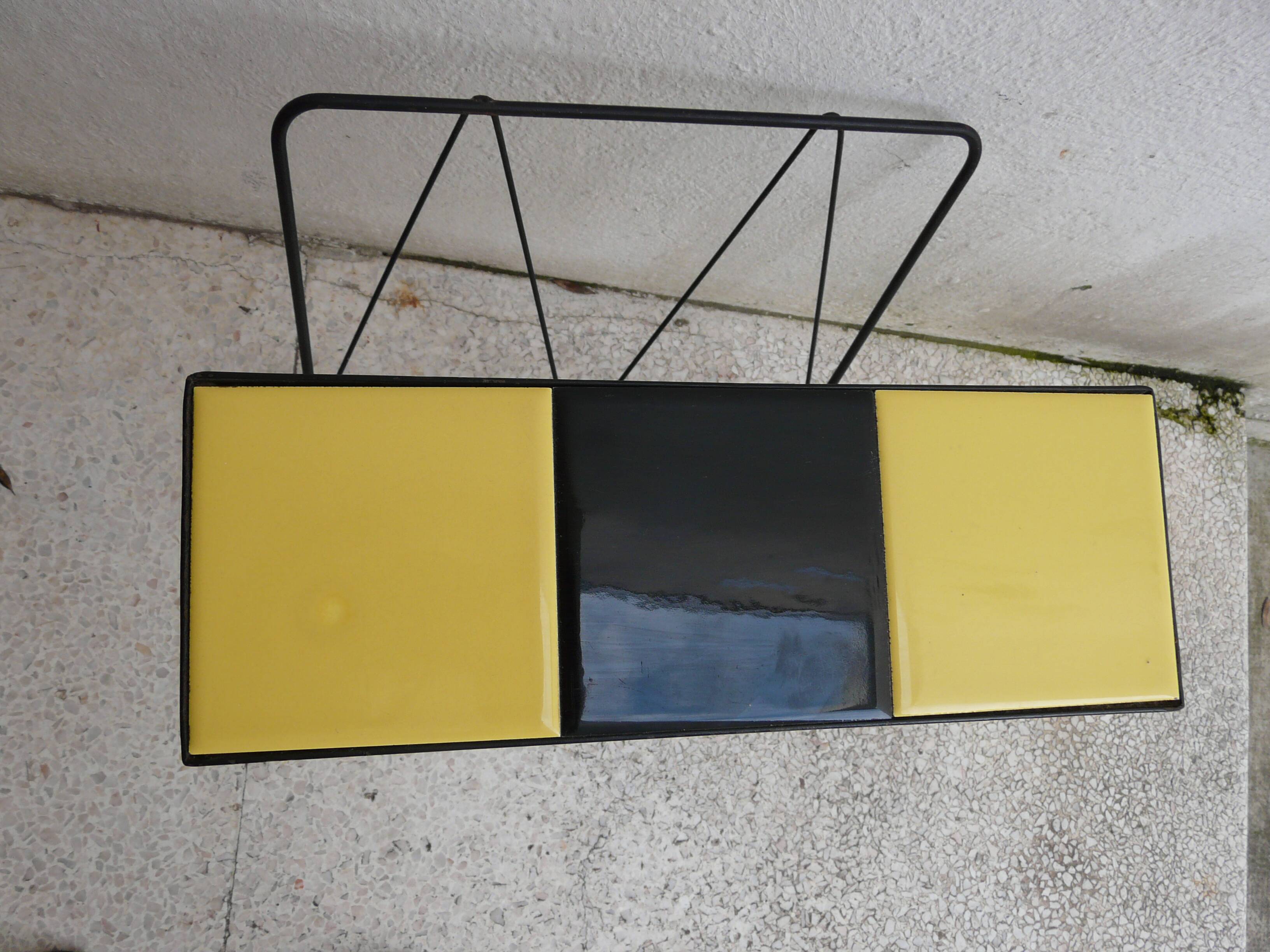 Black metal magazine rack and yellow and black tiled shelf.