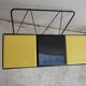 Black metal magazine rack and yellow and black tiled shelf.
