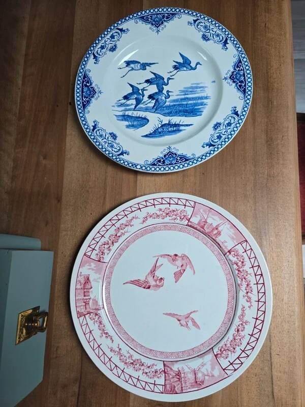 A pair of old flat plates with red and blue bird patterns.