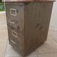 Vintage industrial metal furniture with a rusty effect, featuring two drawers on wheels.