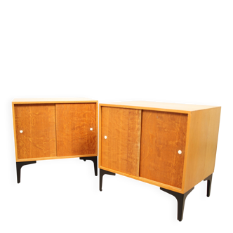 A pair of vintage mid-century bedside tables with oak sliding doors