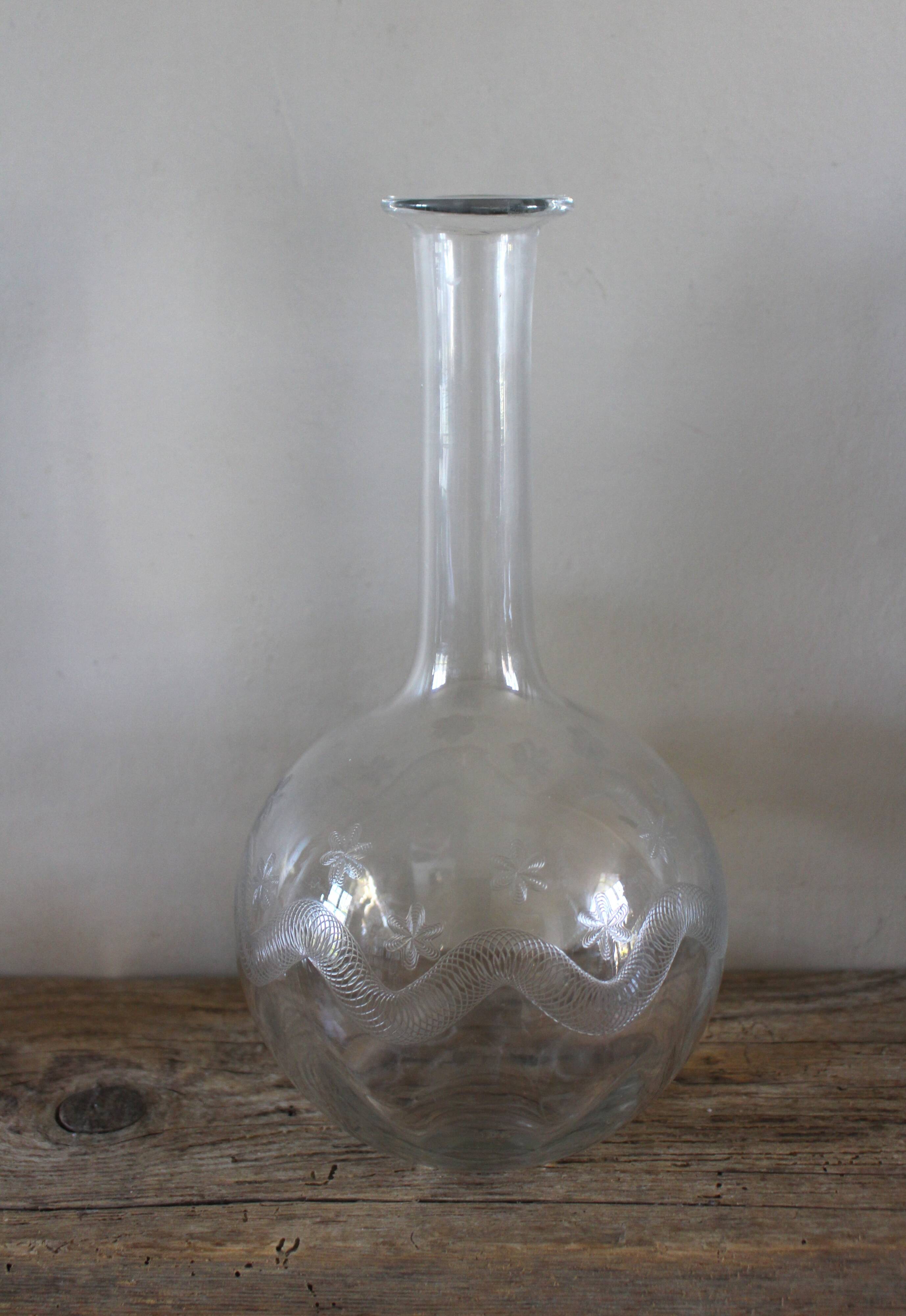 Antique glass carafe with a round belly and floral neck.