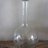 Antique glass carafe with a round belly and floral neck.