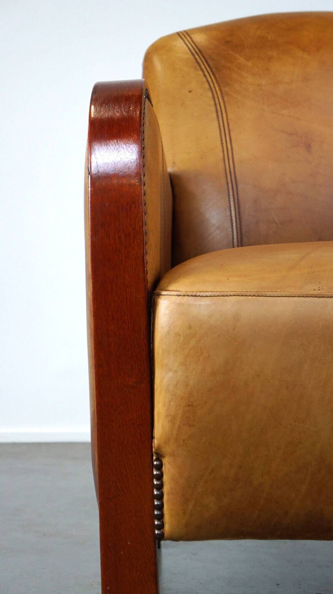 Luxurious cowhide Art Deco design armchair with wooden armrests and cognac-colored leather