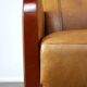 Luxurious cowhide Art Deco design armchair with wooden armrests and cognac-colored leather