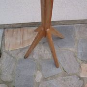 Antique light wood coat rack with splayed legs.