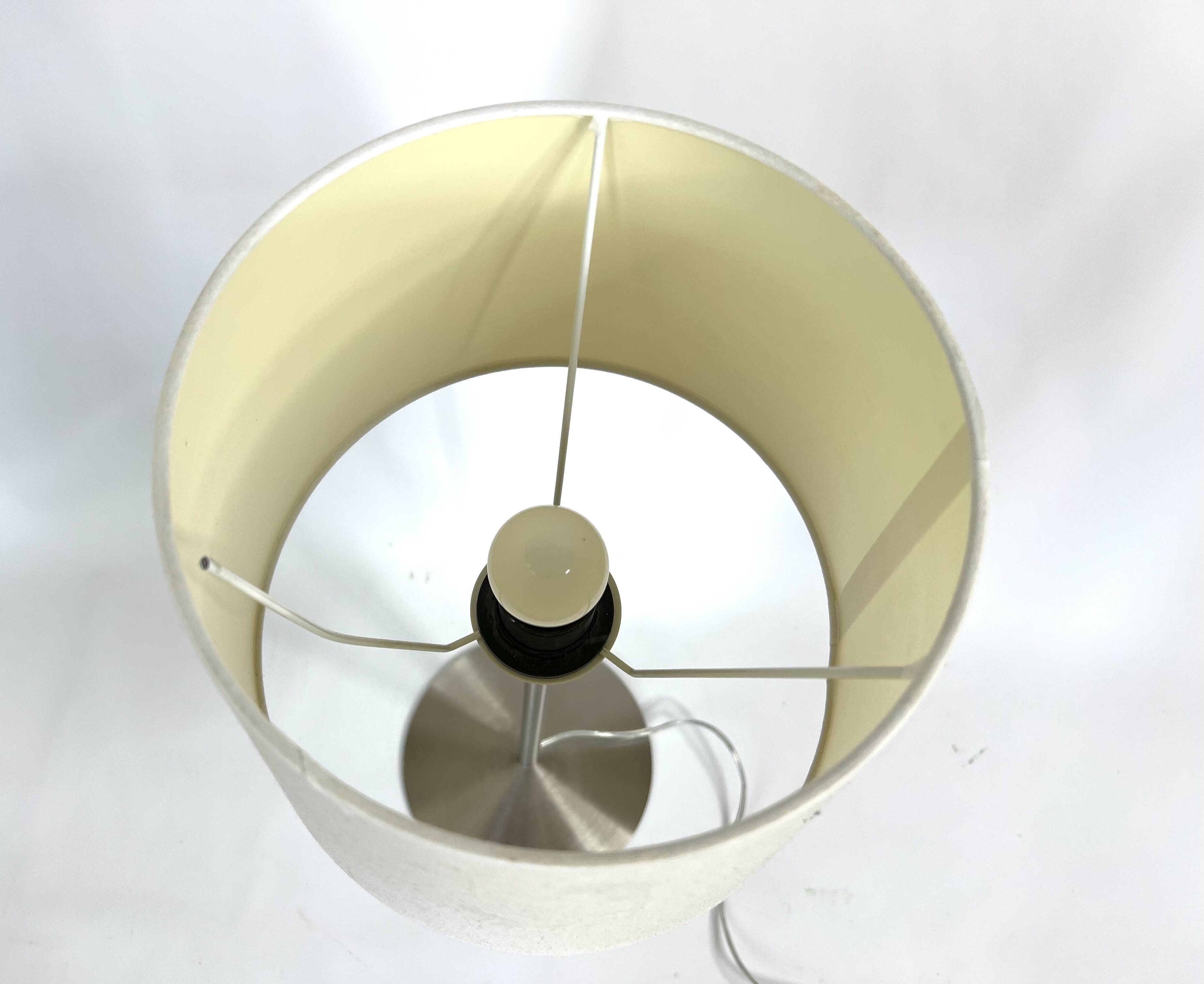 Large brushed metal table lamp with an ecru shade.