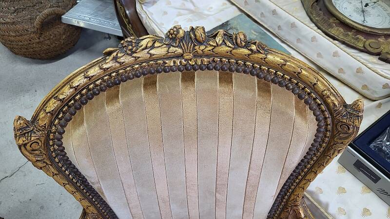 A pair of gilded wooden armchairs in the Louis XVI style.